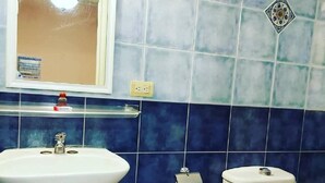 A bathroom with a white sink, a toilet, and a blue-tiled wall. - Hotel de Talavera (Puebla)