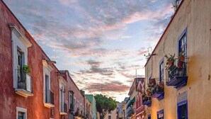 A narrow street lined with colorful buildings, a cobblestone path, and potted plants. - Hotel De Talavera (Puebla)