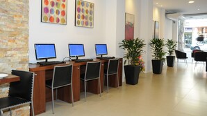 En reception med tre computere, sorte stole og potteplanter.