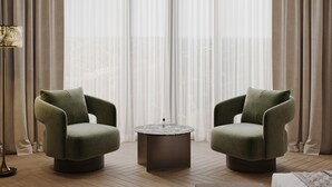 Una sala de estar moderna con dos sillones verdes, una mesa de centro redonda y un sofá.