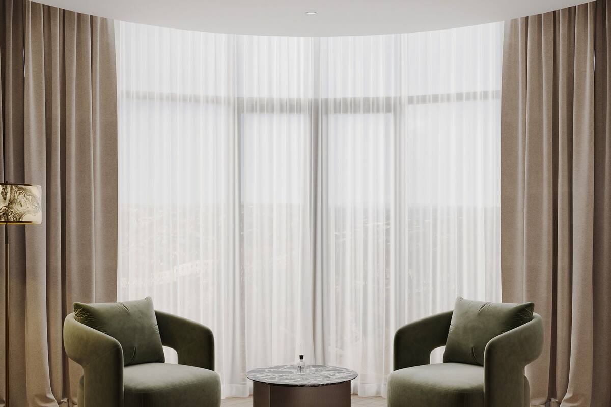 A modern living room with two green armchairs, a round coffee table, and a sofa.