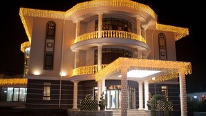 Un edificio imponente con varios balcones y columnas, decorado con luces colgantes.