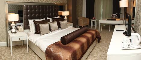 A hotel room with a large bed, a desk, a chair, a coffee maker, and a mirror.