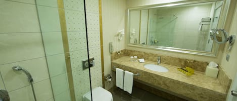 A bathroom with a glass shower enclosure, a toilet, a sink with a mirror, and a towel rack.