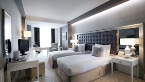 Une chambre d’hôtel avec un grand lit, un lit plus petit, un bureau avec un ordinateur, une télévision et un miroir.