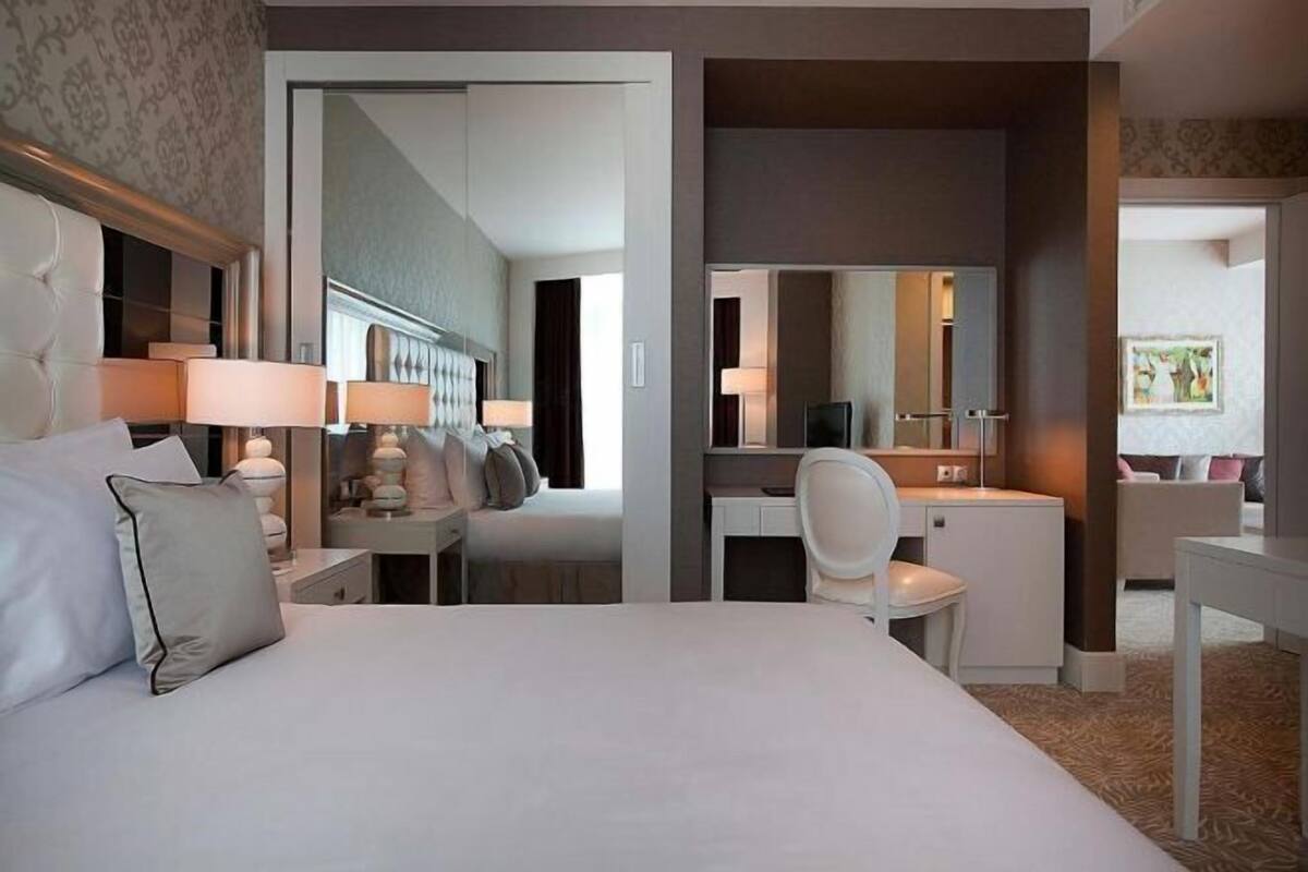 Ein Hotelzimmer mit einem Bett, Nachttischen, einem Schreibtisch, einem Stuhl, einem Spiegel und einem Fernseher.