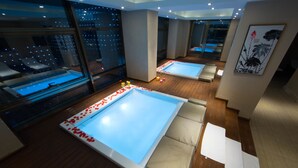 Une salle de spa moderne dotée de deux grandes baignoires, d’un plancher en bois et de grandes fenêtres offrant une vue sur la ville.