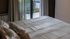 A bedroom with a large bed, a radiator, and a view of a balcony with plants and a railing. - Paradise Departamentos (Mendoza)