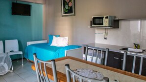 A compact hotel room with a bed, a small kitchenette, a dining table, and a TV mounted on the wall. - Paradise Departamentos (Mendoza)