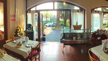 A restaurant with multiple dining tables, a central serving area, and a view of the outside.