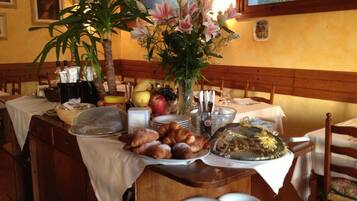 A dining table set with plates, a vase of flowers, and various food items.