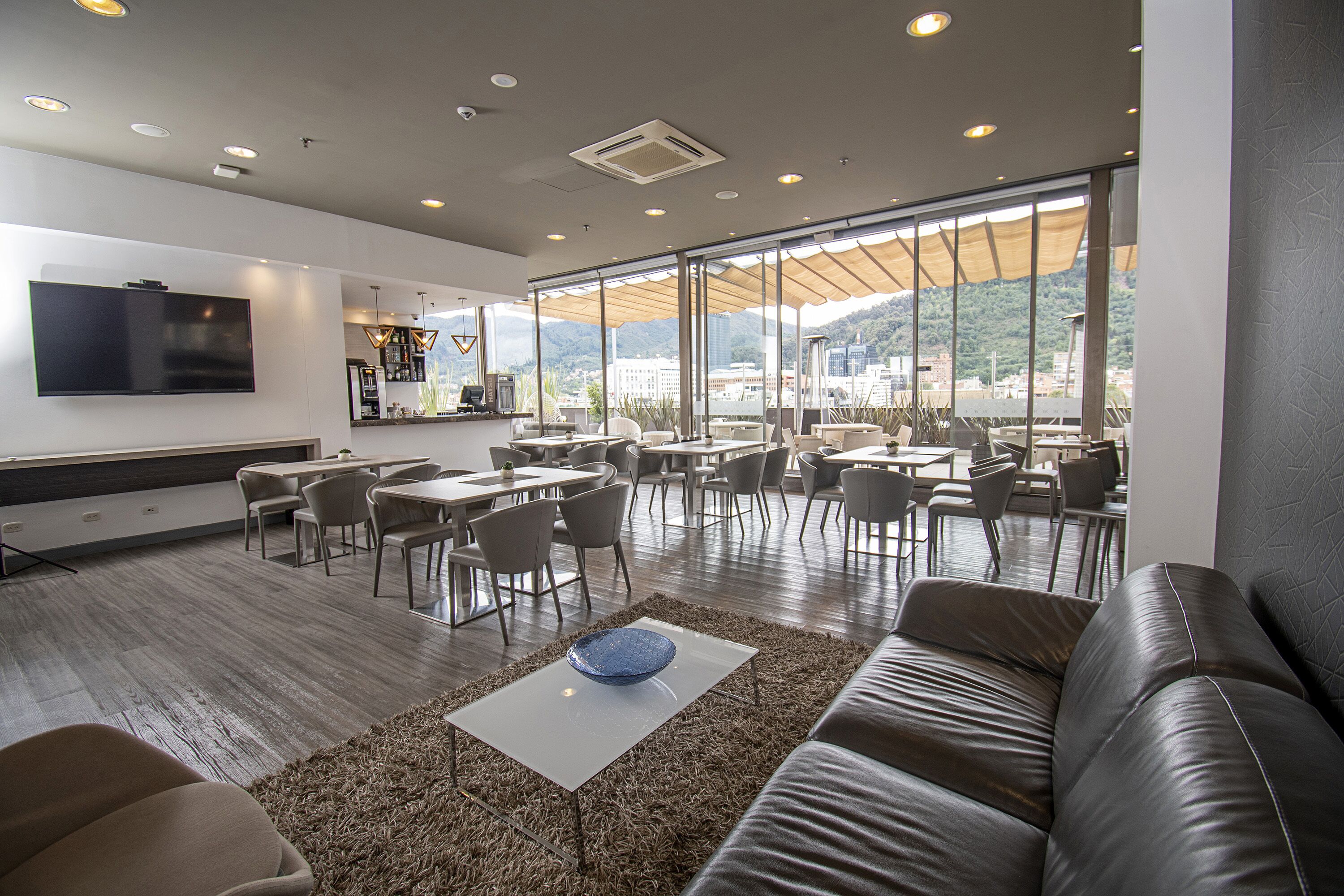 A modern lounge area with a sofa, coffee table, and dining tables.