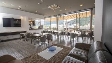 A modern lounge area with a sofa, coffee table, and dining tables.