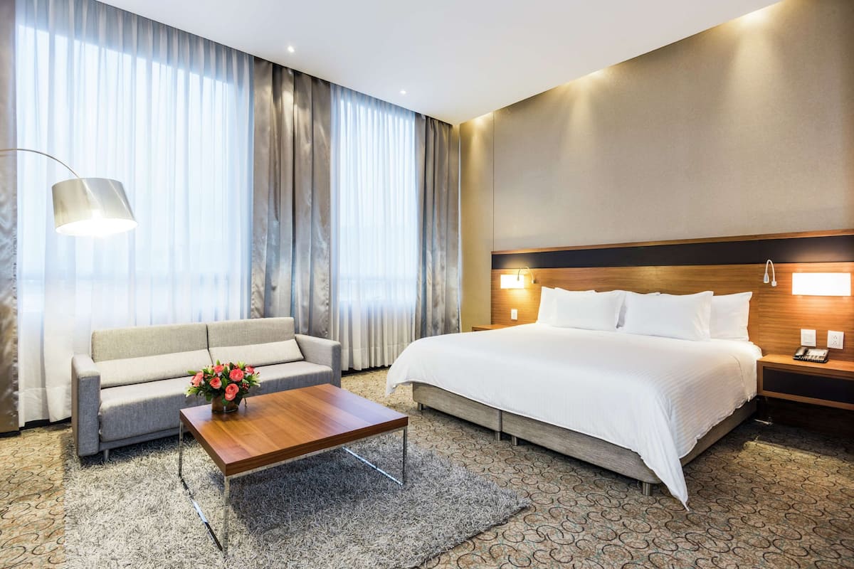 Een hotelkamer met een groot bed, een bank, een bijzettafeltje en een lamp.
