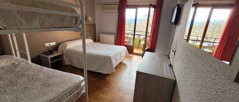A hotel room with two beds, a desk, a chair, a TV, and a window with a view of the outdoors.