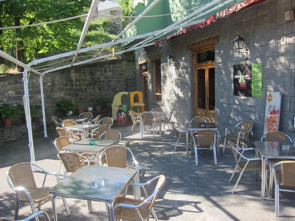 An outdoor patio with tables and chairs, a stone wall, and a sign for a hotel.