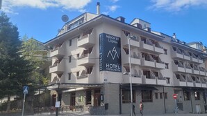 Un hotel de varios pisos con balcones, una terraza y un letrero que indica que es hotel y restaurante.
