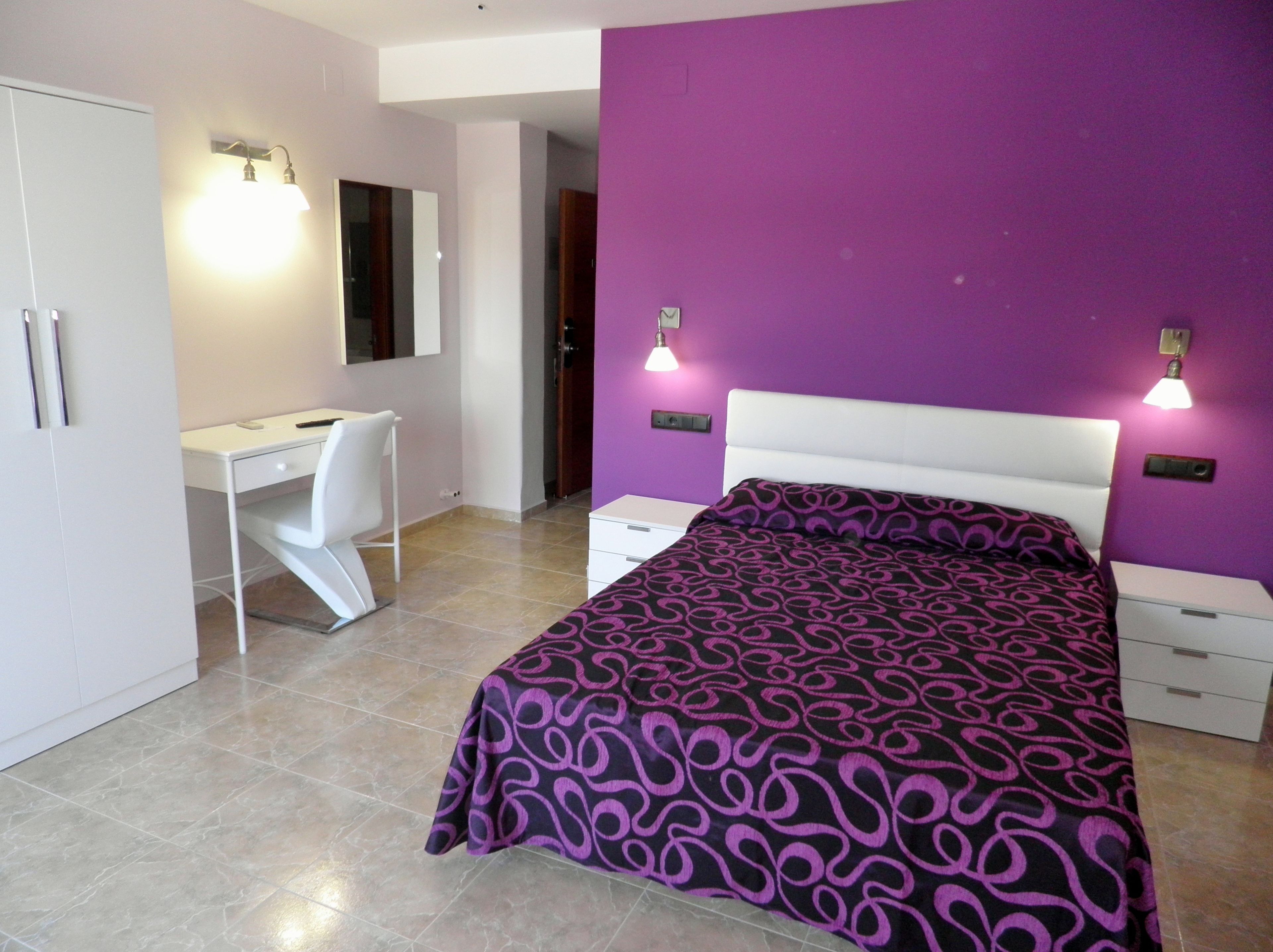 Un dormitorio con cama, escritorio y armario.