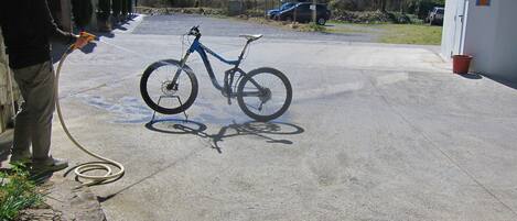 A bicycle parked in a concrete area with a hose.