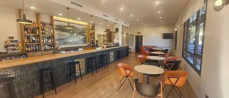 A bar area with a counter, stools, and a seating area with tables and chairs.