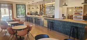 A modern cafe with a bar area, seating, and a view of the outdoors.