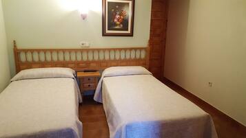 A twin room with two beds, a wooden headboard, a nightstand, and a framed painting on the wall.