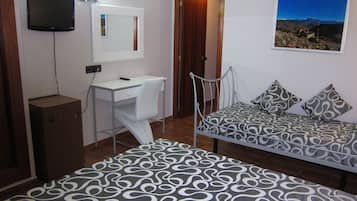 A bedroom with a bed, a desk, a chair, a TV, and a door.