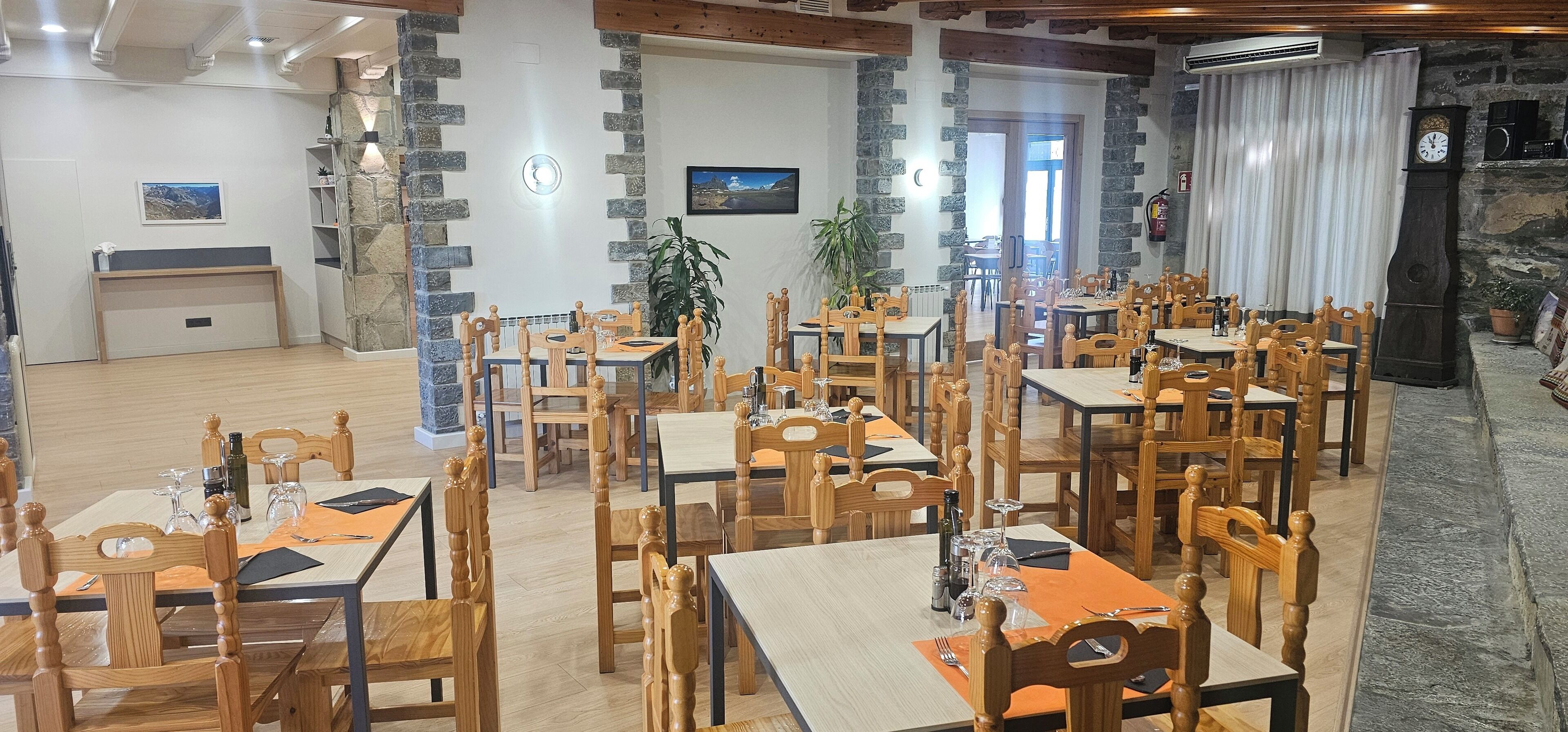 A restaurant with wooden tables and chairs, stone walls, and a clock.