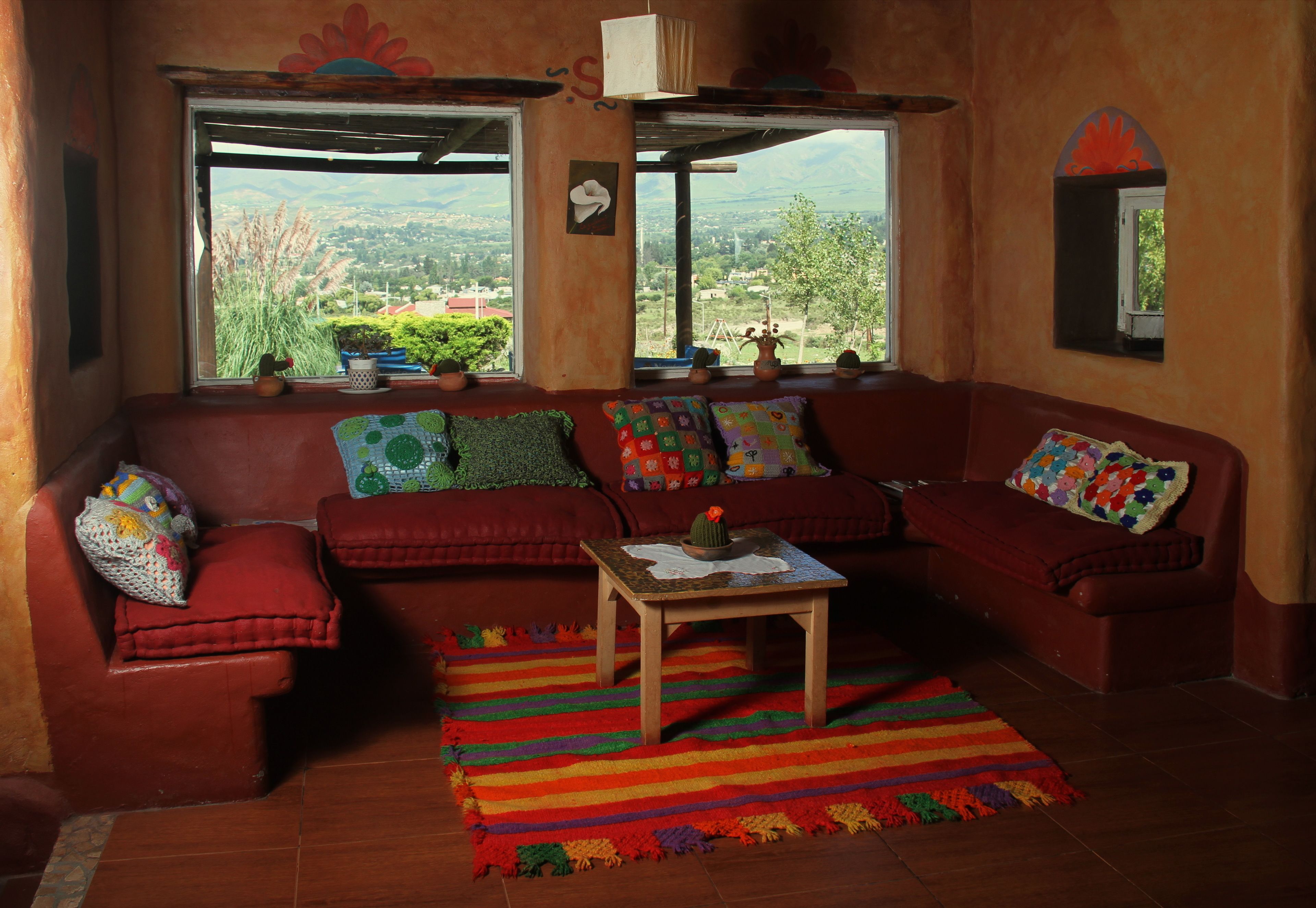 A cozy living room with a red sofa, a wooden coffee table, and a colorful rug.