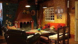 A cozy living room with a fireplace, a sofa, a coffee table, and a dining table. - Posada La Guadalupe (Tafi del Valle)