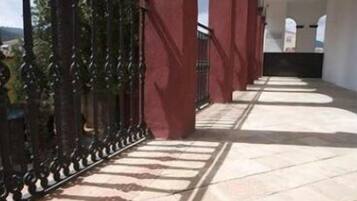 Un couloir avec un mur rouge et un portail en métal noir.