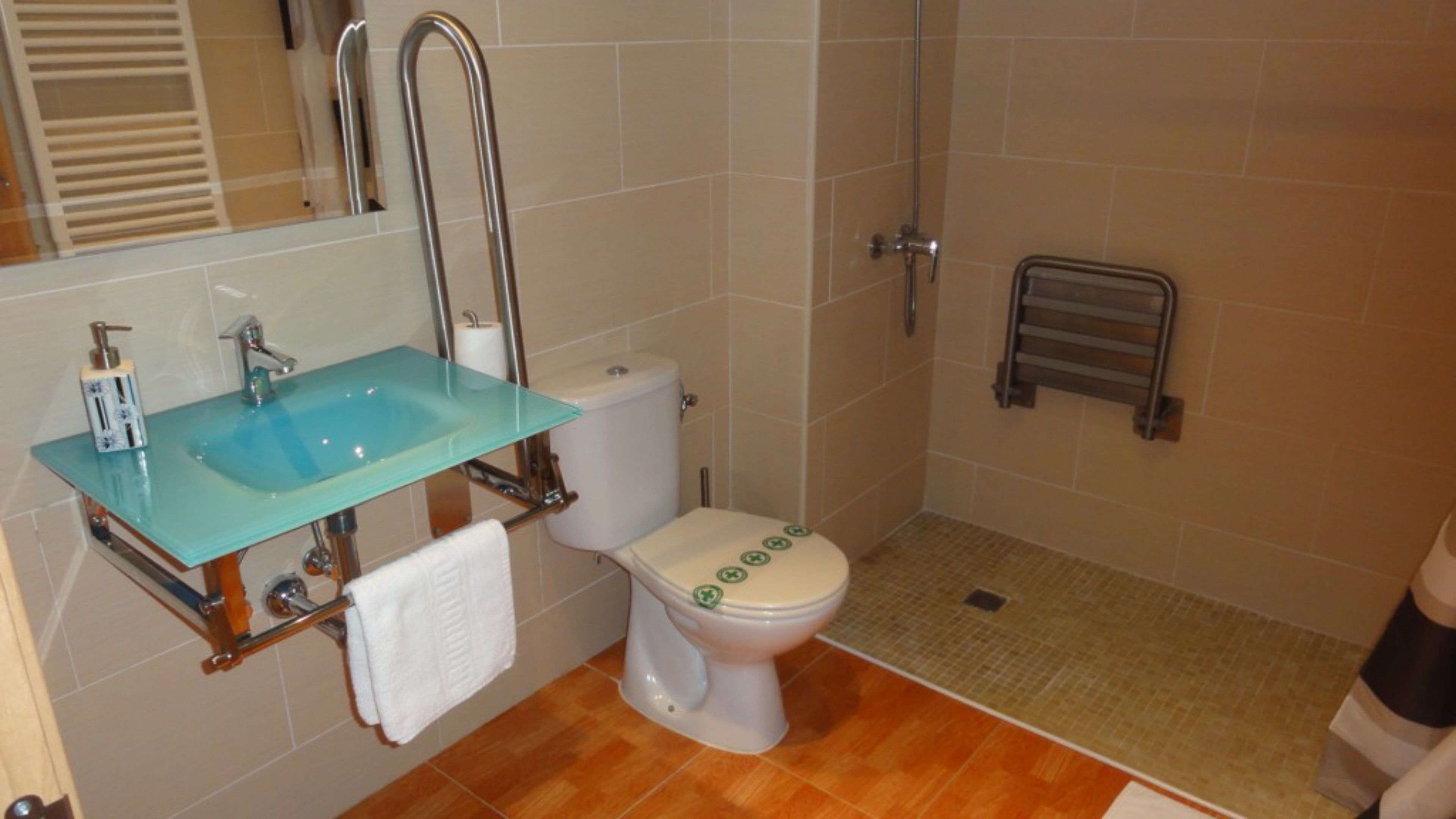 Een badkamer met een glazen wastafel, toilet en douche.