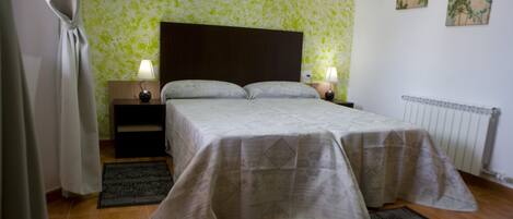 A bedroom with a bed, nightstands, lamps, and a radiator.