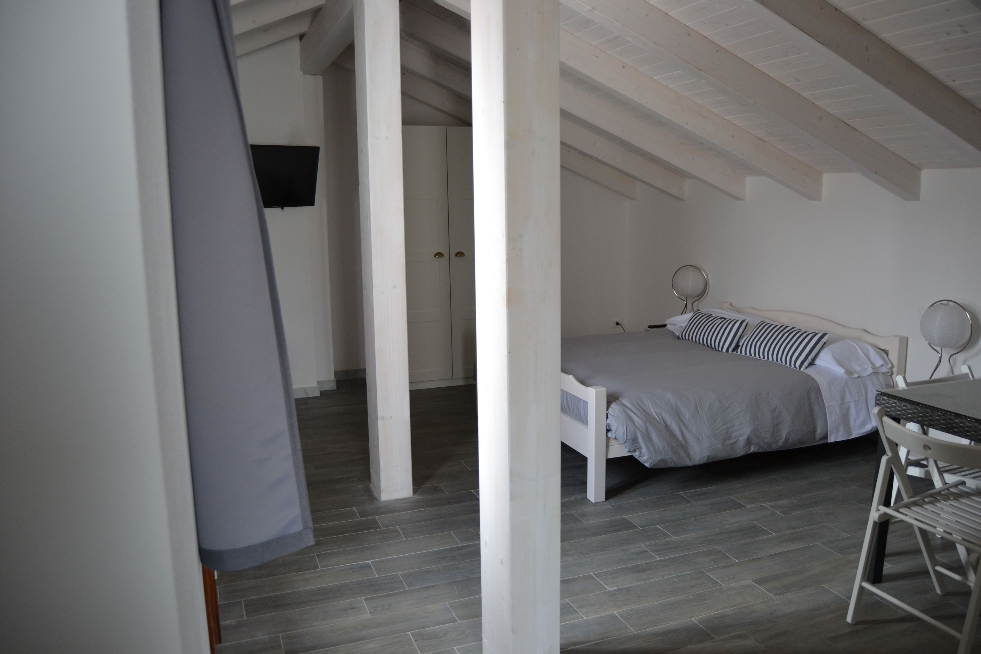 Une chambre avec un lit, une table et une chaise. Il y a une porte et une fenêtre dans la pièce.