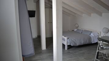 Une chambre avec un lit, une table et une chaise. Il y a une porte et une fenêtre dans la pièce.
