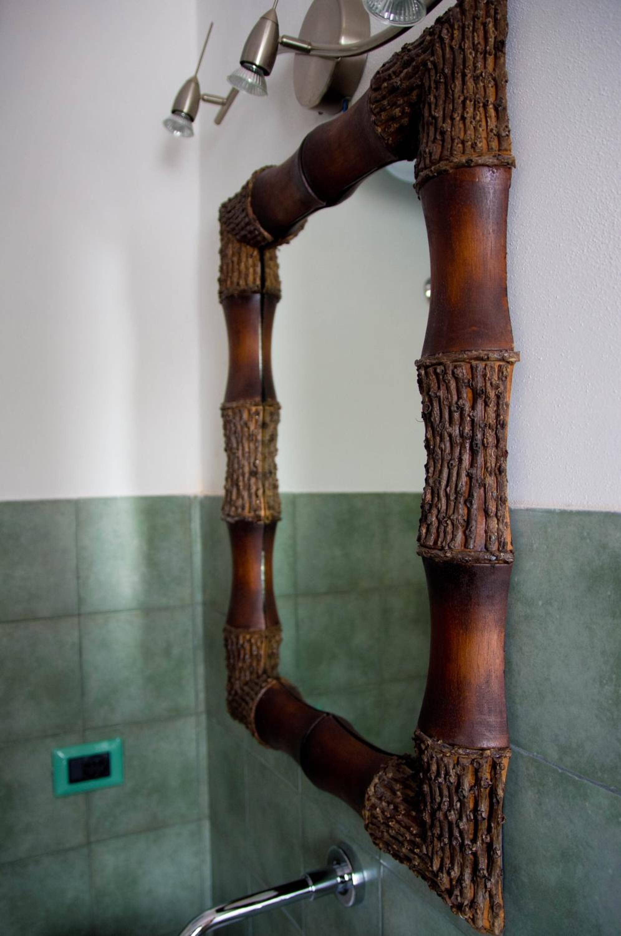 A bathroom with a wooden handrail and a green tiled wall.