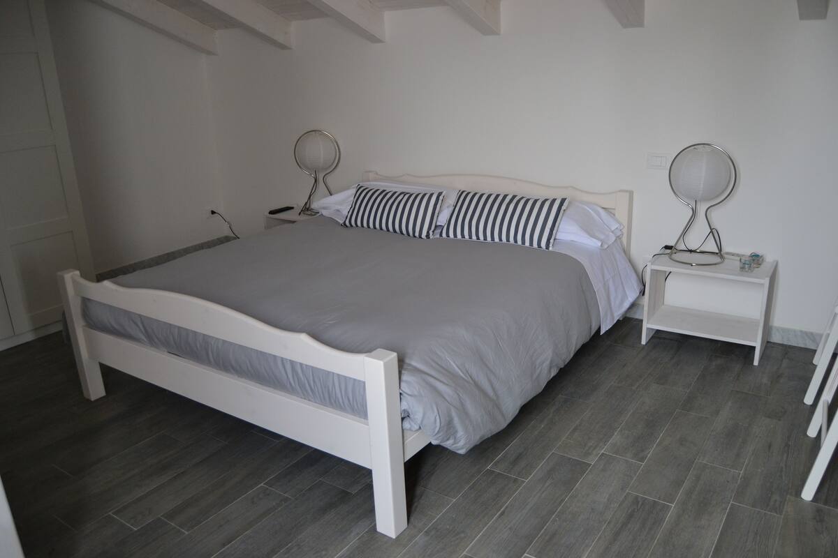 Un dormitorio con una cama, dos mesitas de noche y un espejo sobre cada una.