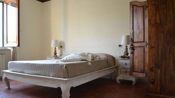Une chambre à coucher avec un grand lit, des tables de chevet avec des lampes, une armoire en bois et une fenêtre avec des rideaux.