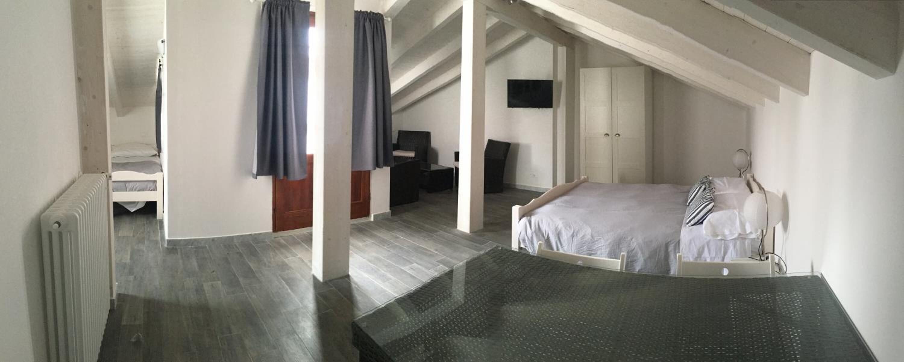 A bedroom with a bed, a chair, a desk, and a wardrobe.