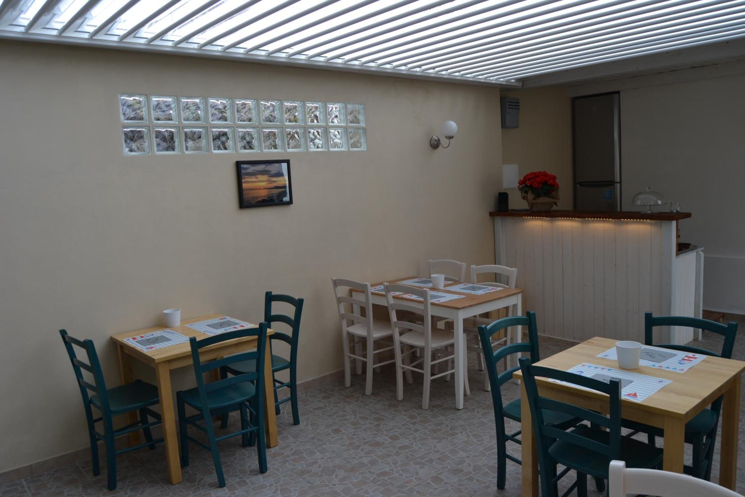 Ein Essbereich mit hohen Decken, einer Wand mit einer Reihe quadratischer Fenster und einer Theke mit einem Blumenstrauß.