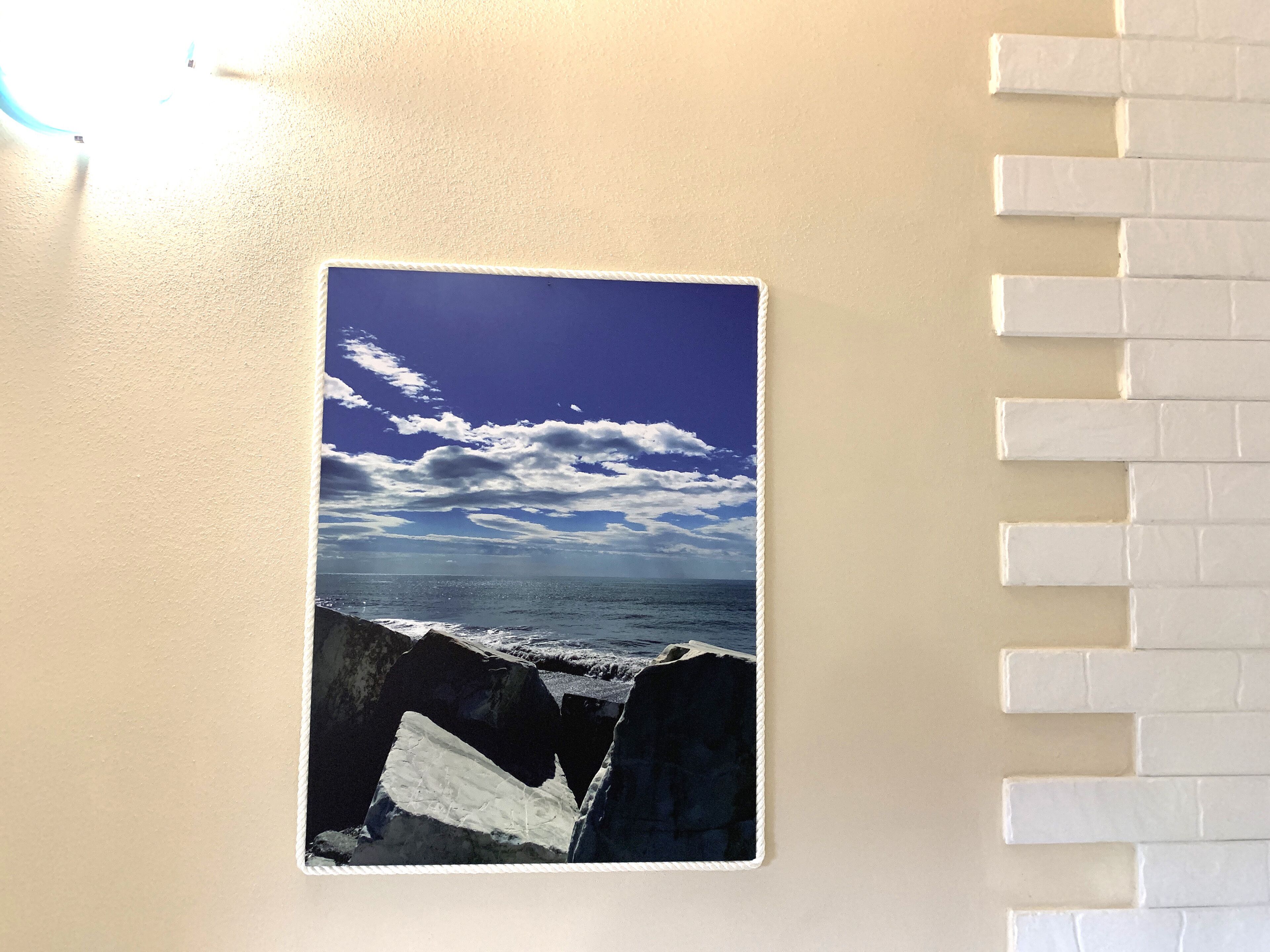 Ein gerahmtes Foto einer Küstenlandschaft mit Wellen und blauem Himmel.