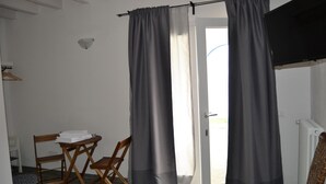 Quarto com área de jantar, televisão e vista pela porta.