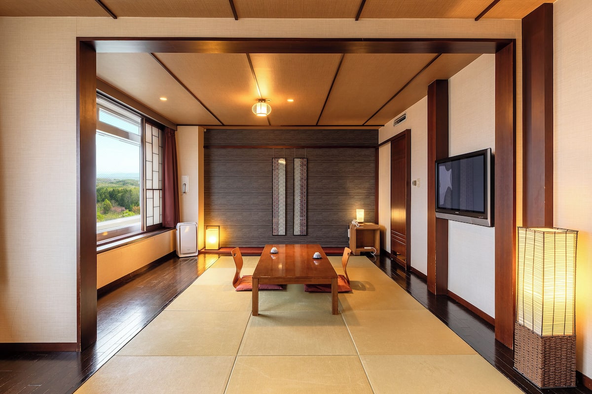 Une pièce de style japonais traditionnel, avec un sol recouvert de tatamis, une petite table en bois et des portes coulissantes.
