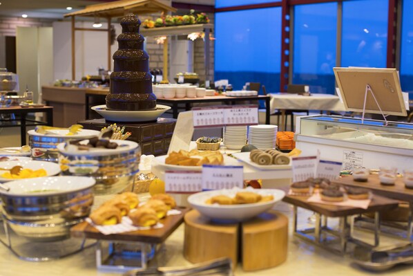 A buffet with various food items and a chocolate fountain.