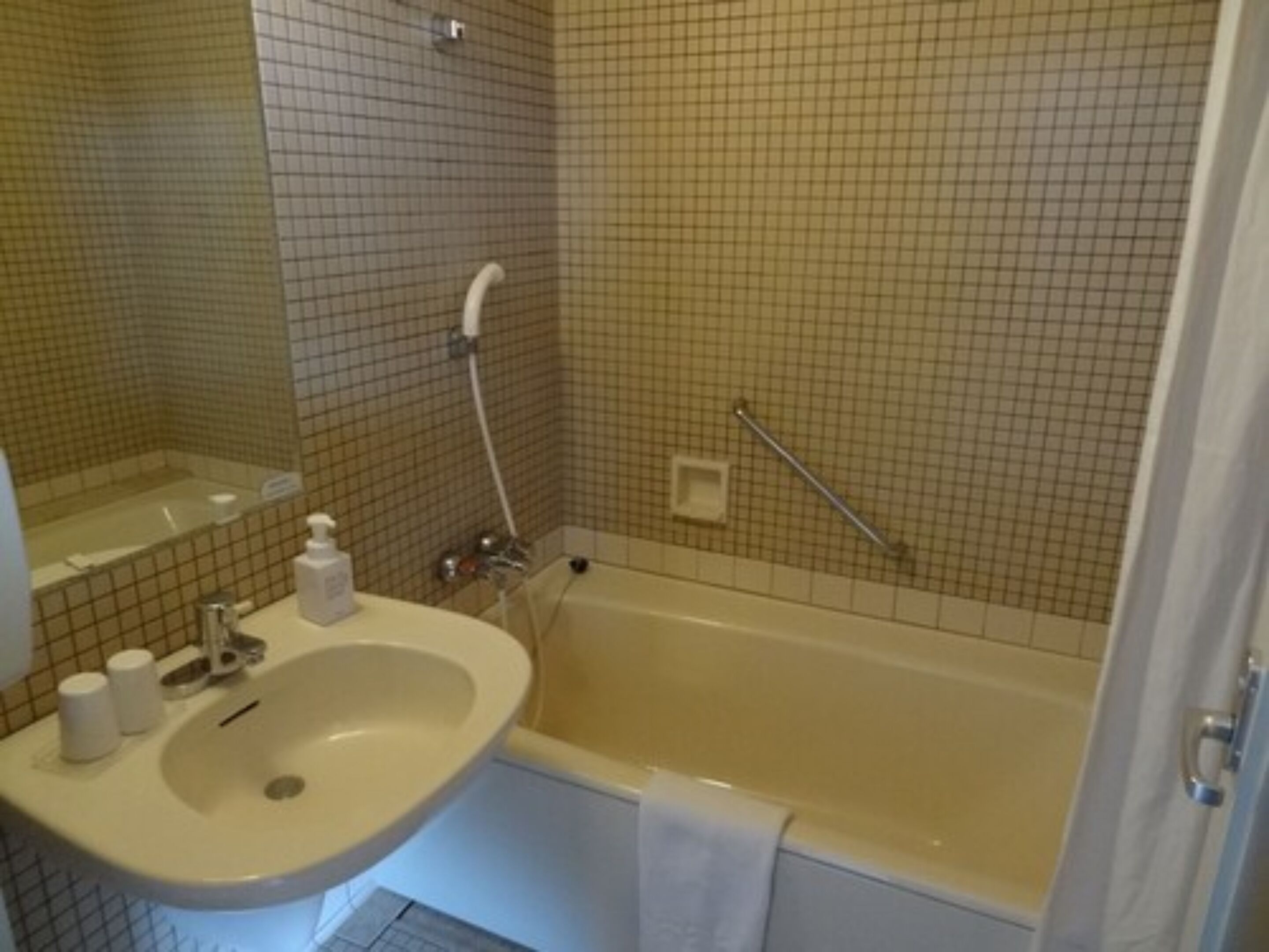 A bathroom with a sink, mirror, and bathtub.