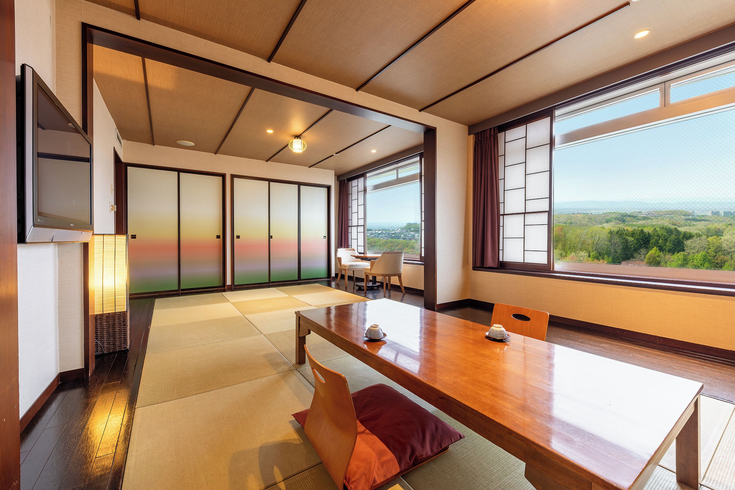 Una habitación tradicional japonesa con suelo de tatami, una mesa de madera y puertas correderas.