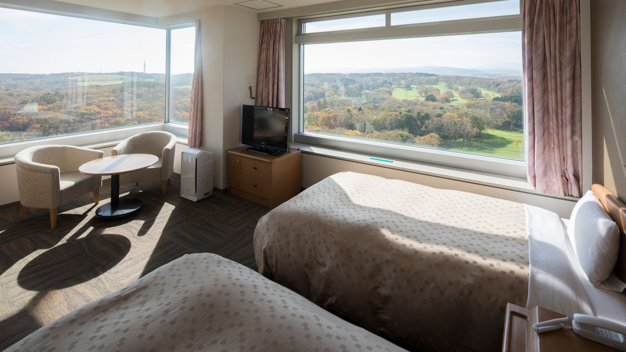 A hotel room with two beds, a TV, a desk, and a chair.