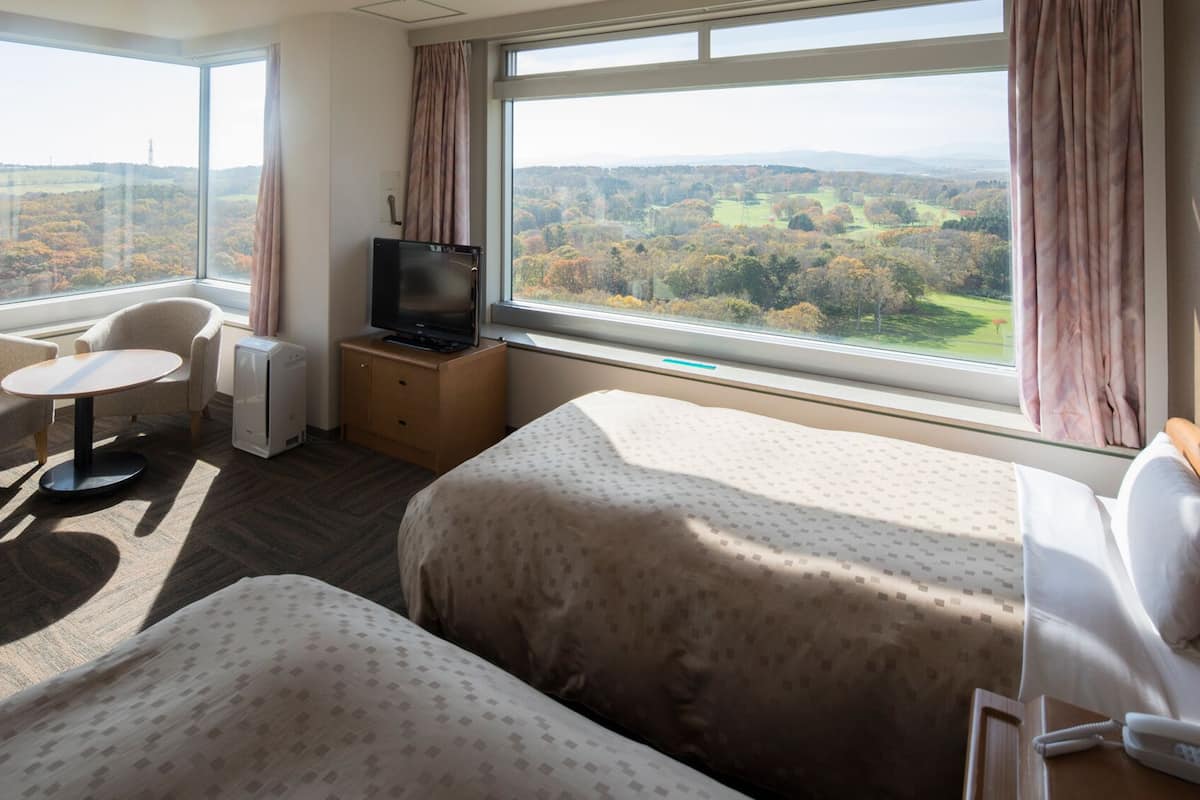 Une chambre d’hôtel avec deux lits, une télévision, un bureau et une chaise.