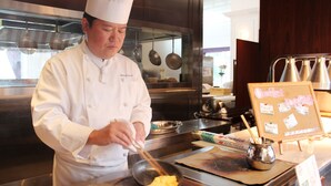 A chef in a white uniform cooking in a professional kitchen.