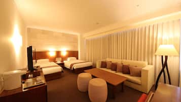 A hotel room with a bed, a sofa, a coffee machine, and a lamp.